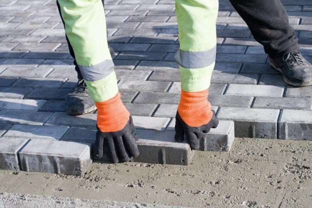 Concrete contractor placing brick pavers by hand for residential driveway installation in Strongsville, OH