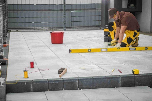 Contractor using level tool to align large concrete patio slabs during installation in Strongsville, OH