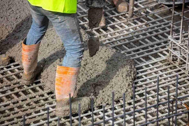 Worker pouring fresh concrete over steel rebar grid for structural slab construction in Strongsville, OH